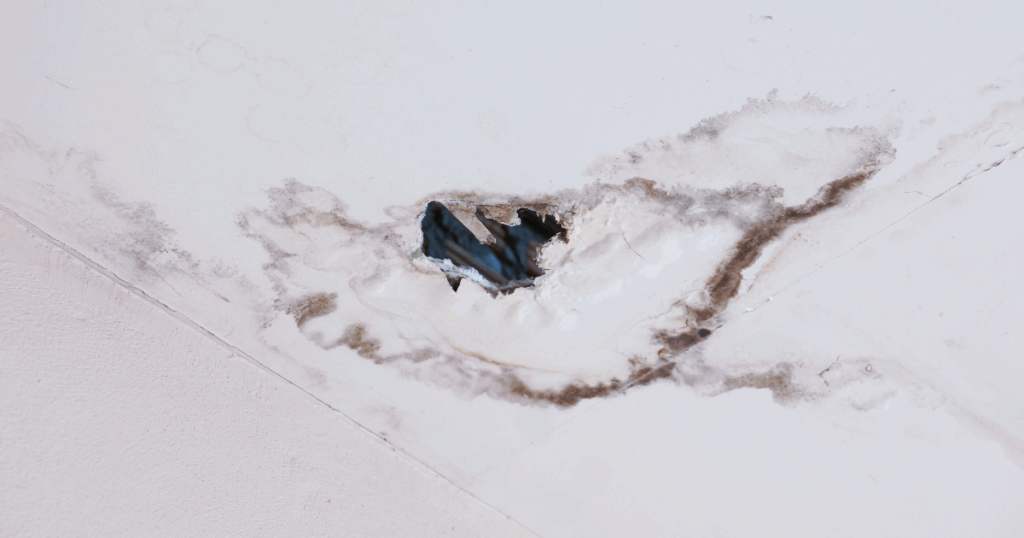 corner of roof with large water stain and hole