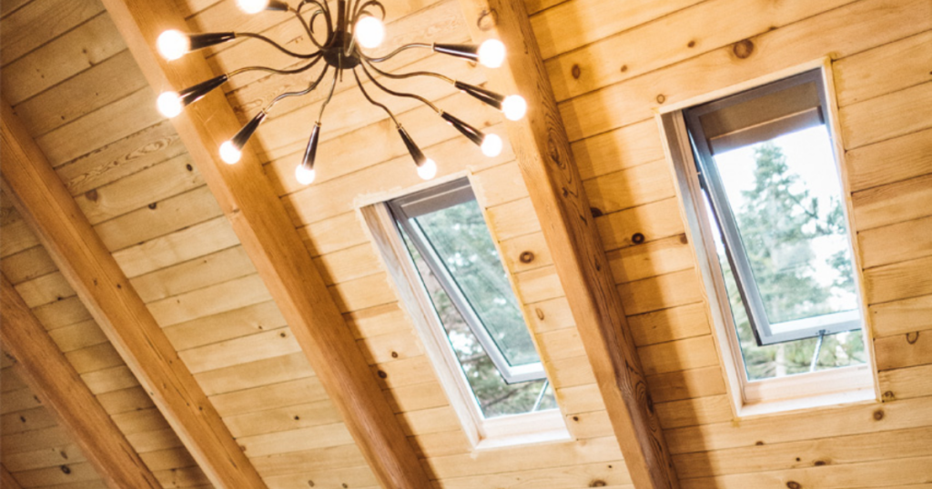 view from inside a home of two opened skylights against wood walls