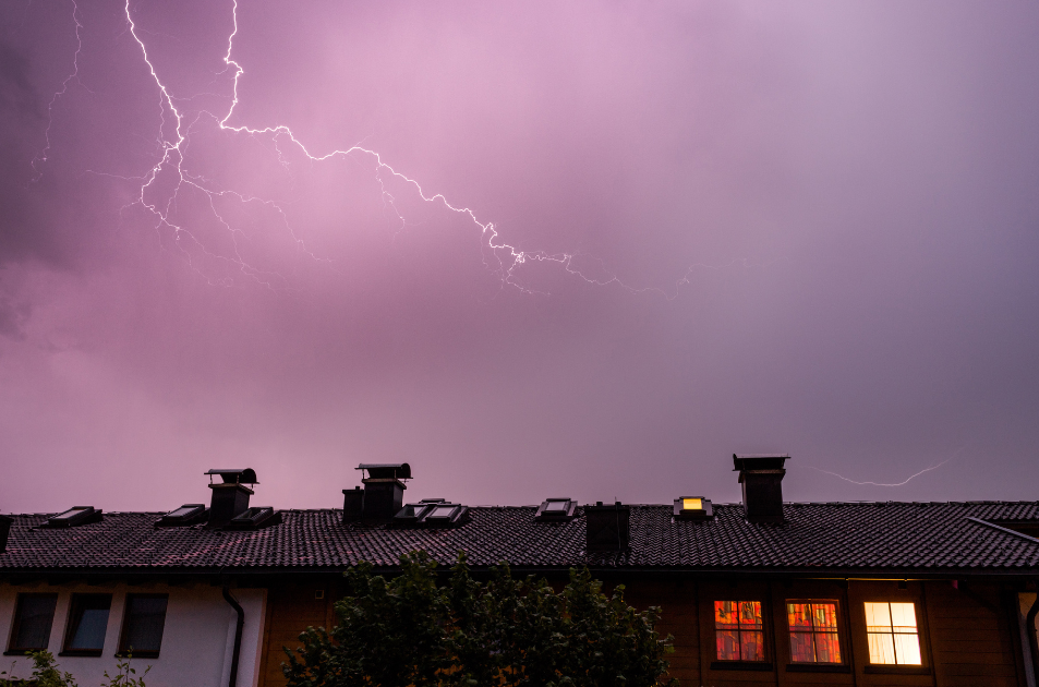 lightning in purple skies above roof of house