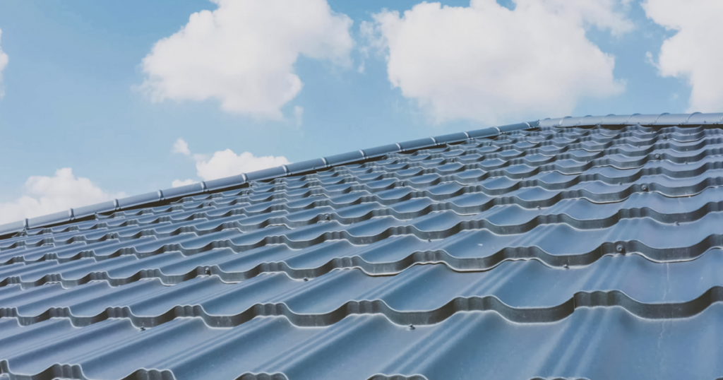 view of metal roof against blue sky and light white clouds