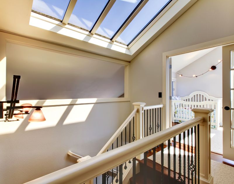 staircase of a home with a skylight above and a nursery room in the background