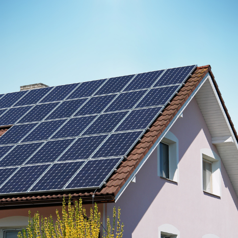 a residential roof with solar panels and the sun shining high above, powering them.