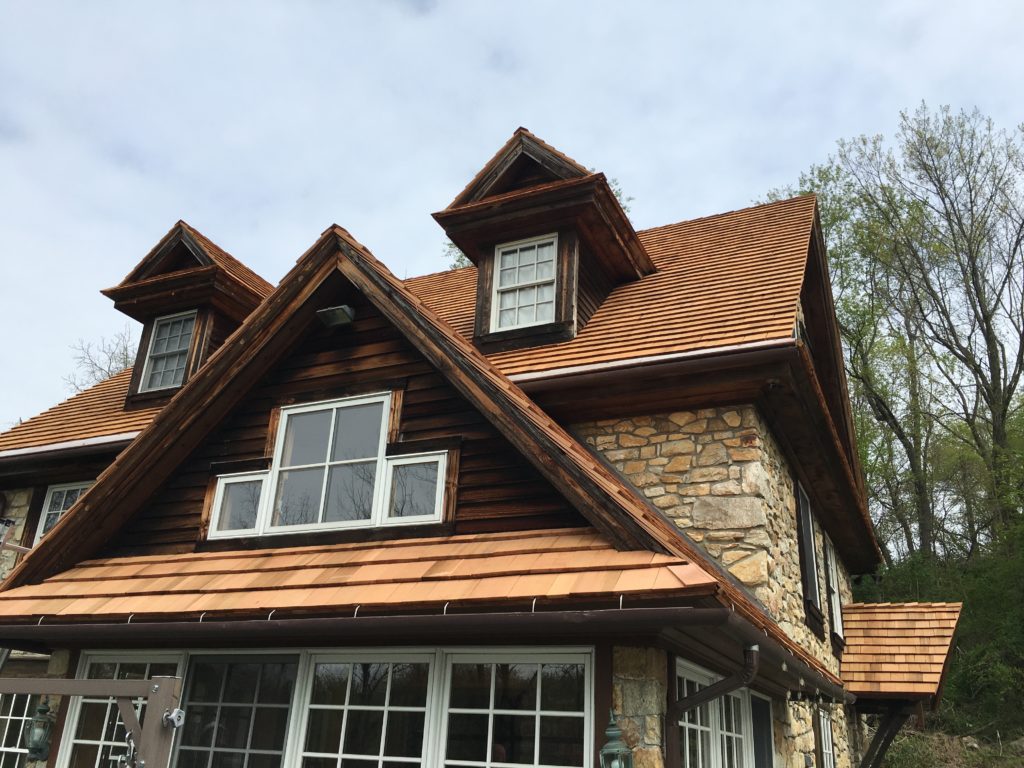 A cabin style house with cobblestone extior and a cedar roof.