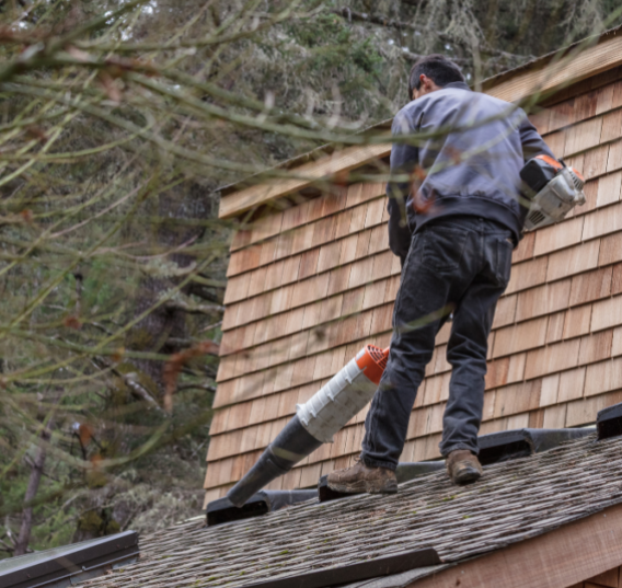 man using leaf blower on roof