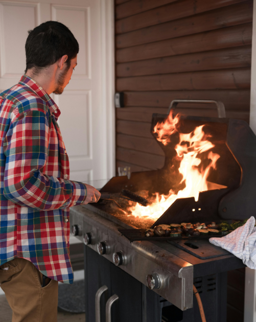 man using grill close to home's siding