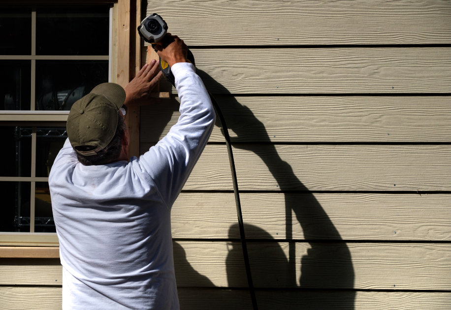 man using drill on siding