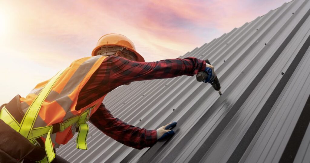 man drilling on metal roof