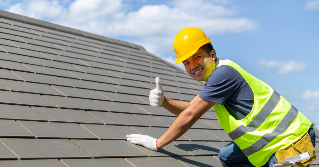 roofing contractor on home's roof giving a thumbs up