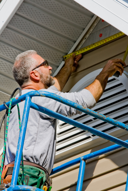 man carefully measuring siding around window