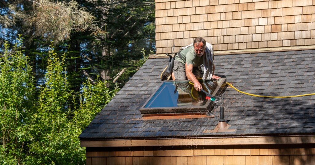 man on roof cleaning shingles
