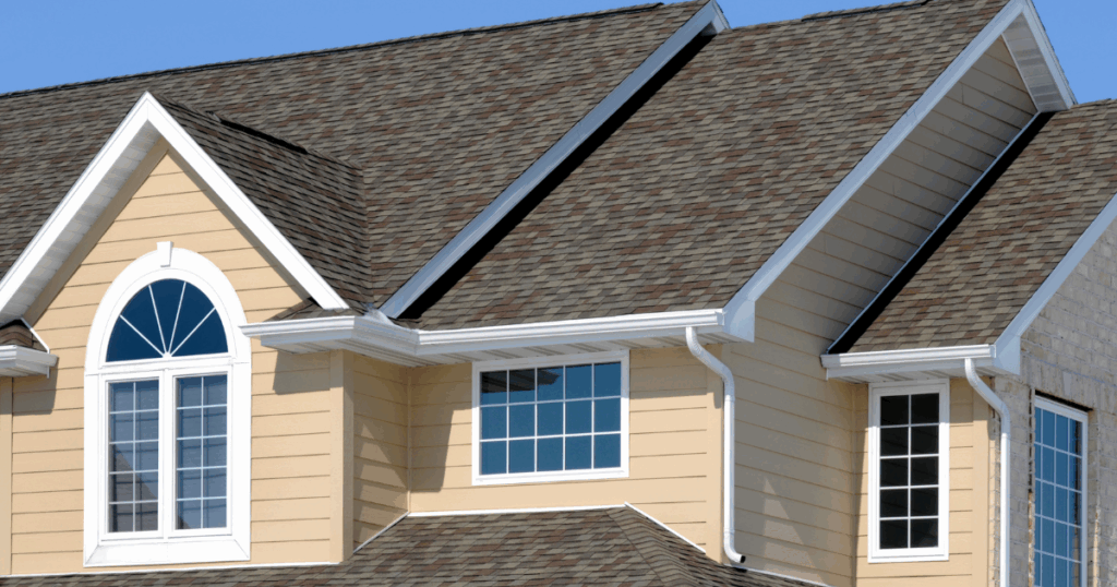 light yellow home with medium brown synthetic shingle roof