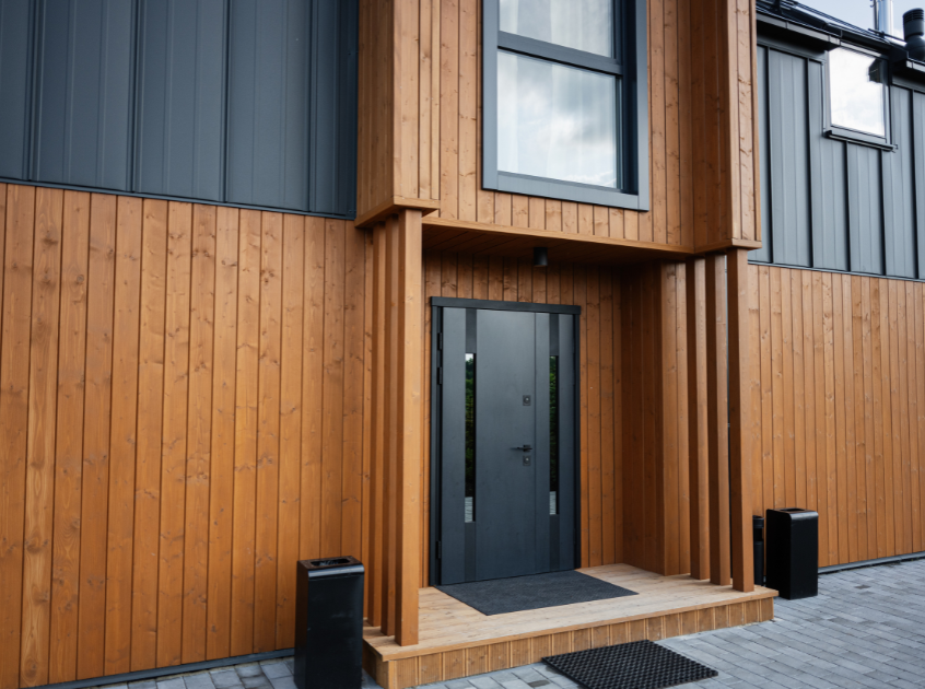 Wooden vertical siding on a house, with metal accents.