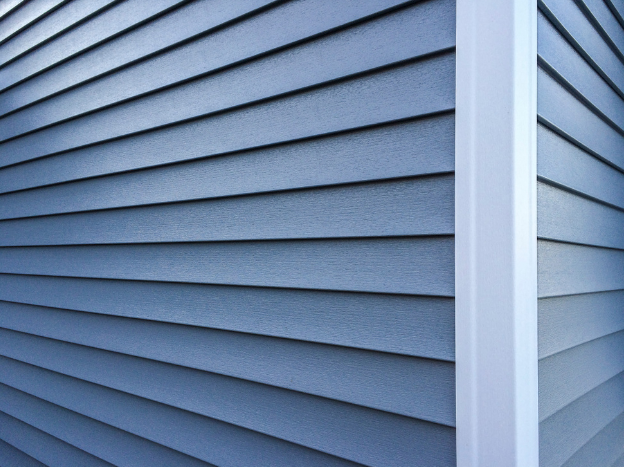 The corner of a house that has gray vinyl siding